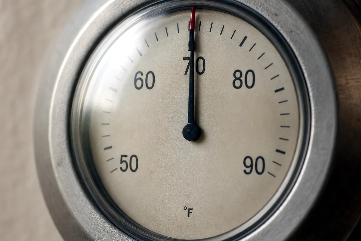 Close-up of a round analog thermostat dial set to 72 degrees.